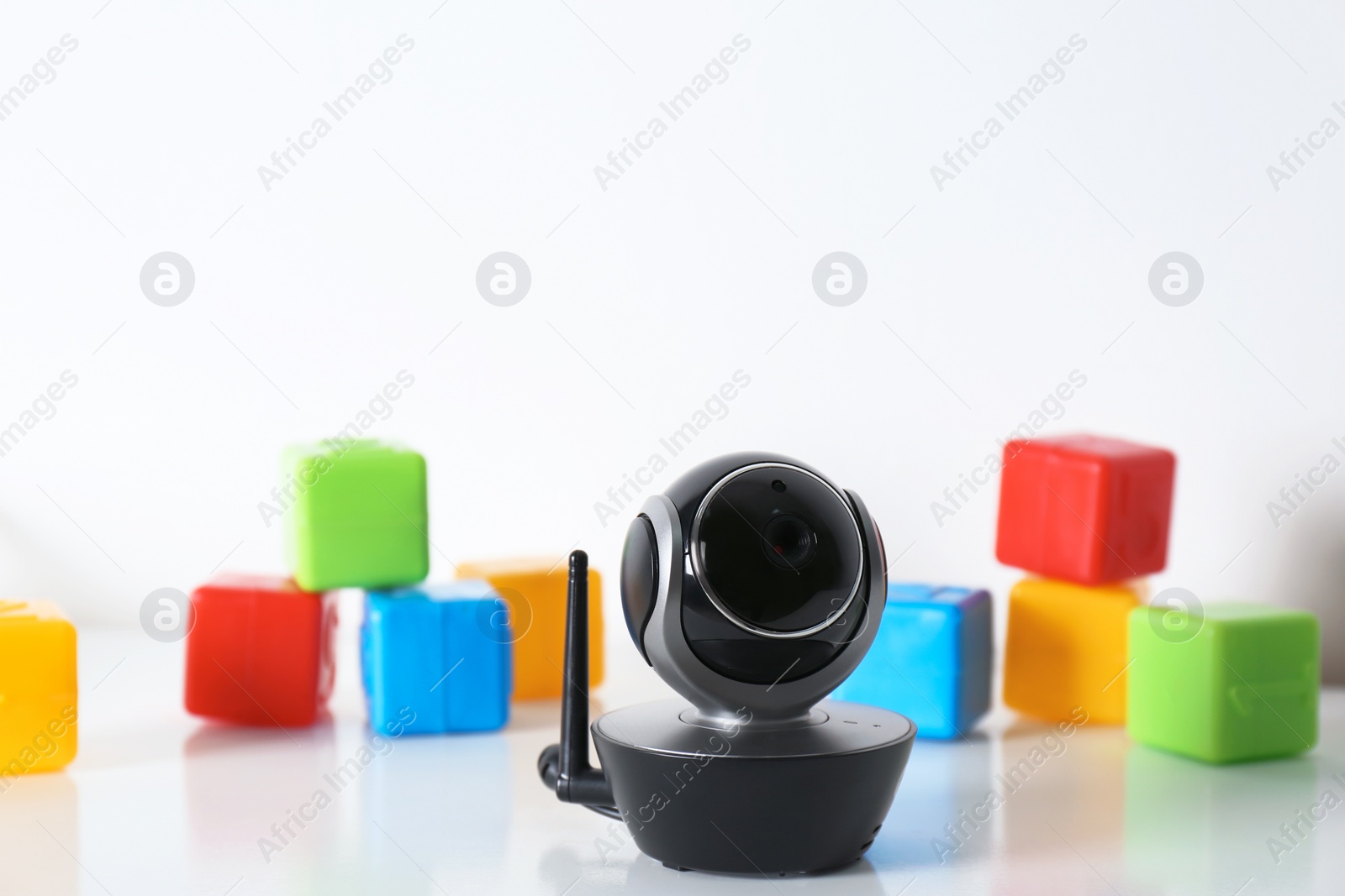 Photo of Modern CCTV security camera and colorful cubes on table against white background. Space for text
