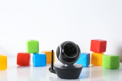 Modern CCTV security camera and colorful cubes on table against white background. Space for text