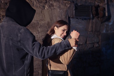 Photo of Criminal attacking young woman in alley at night. Self defense concept