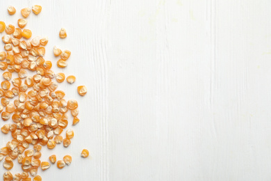 Raw dry corn seeds and space for text on white wooden background, flat lay. Vegetable planting