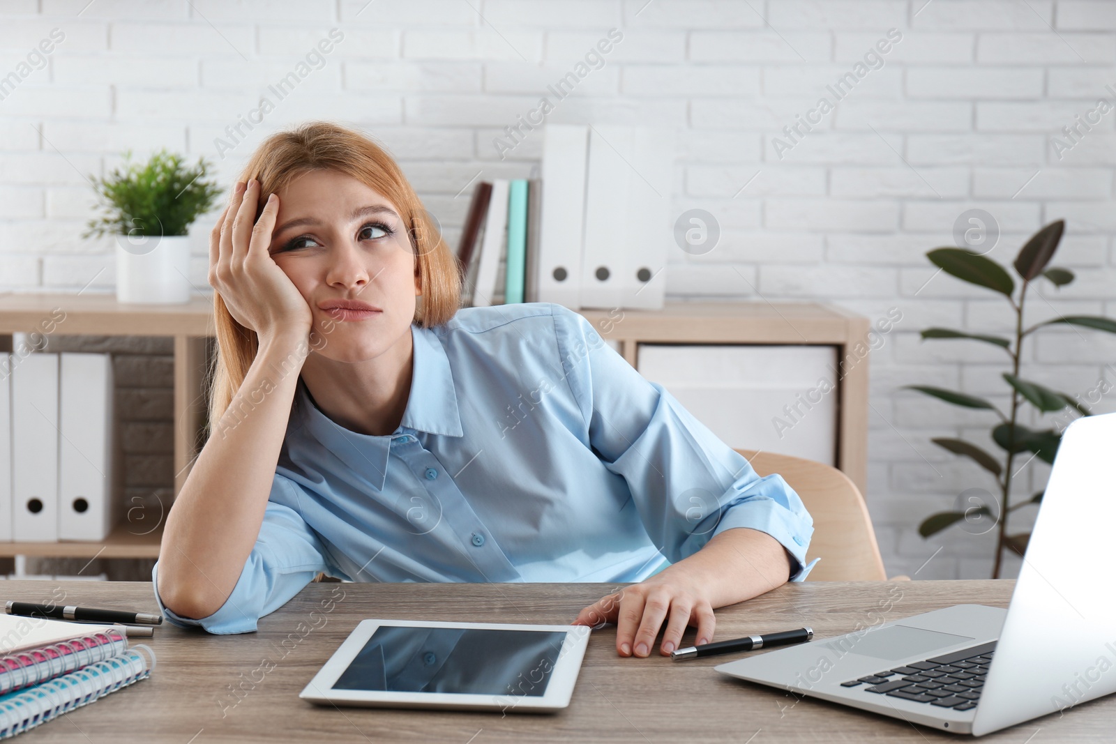 Photo of Lazy employee wasting time at table in office