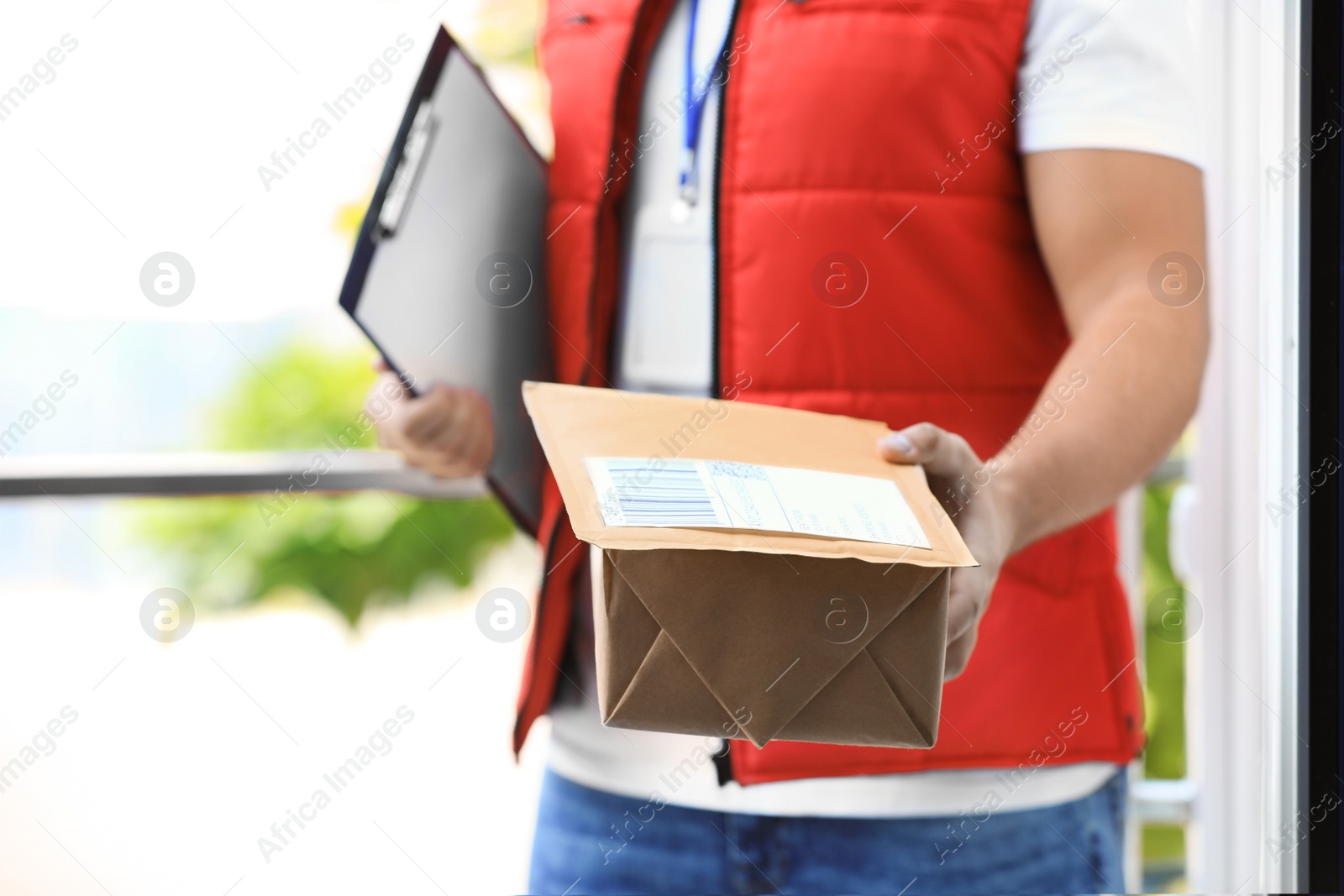 Photo of Young courier delivering parcels on doorstep, closeup