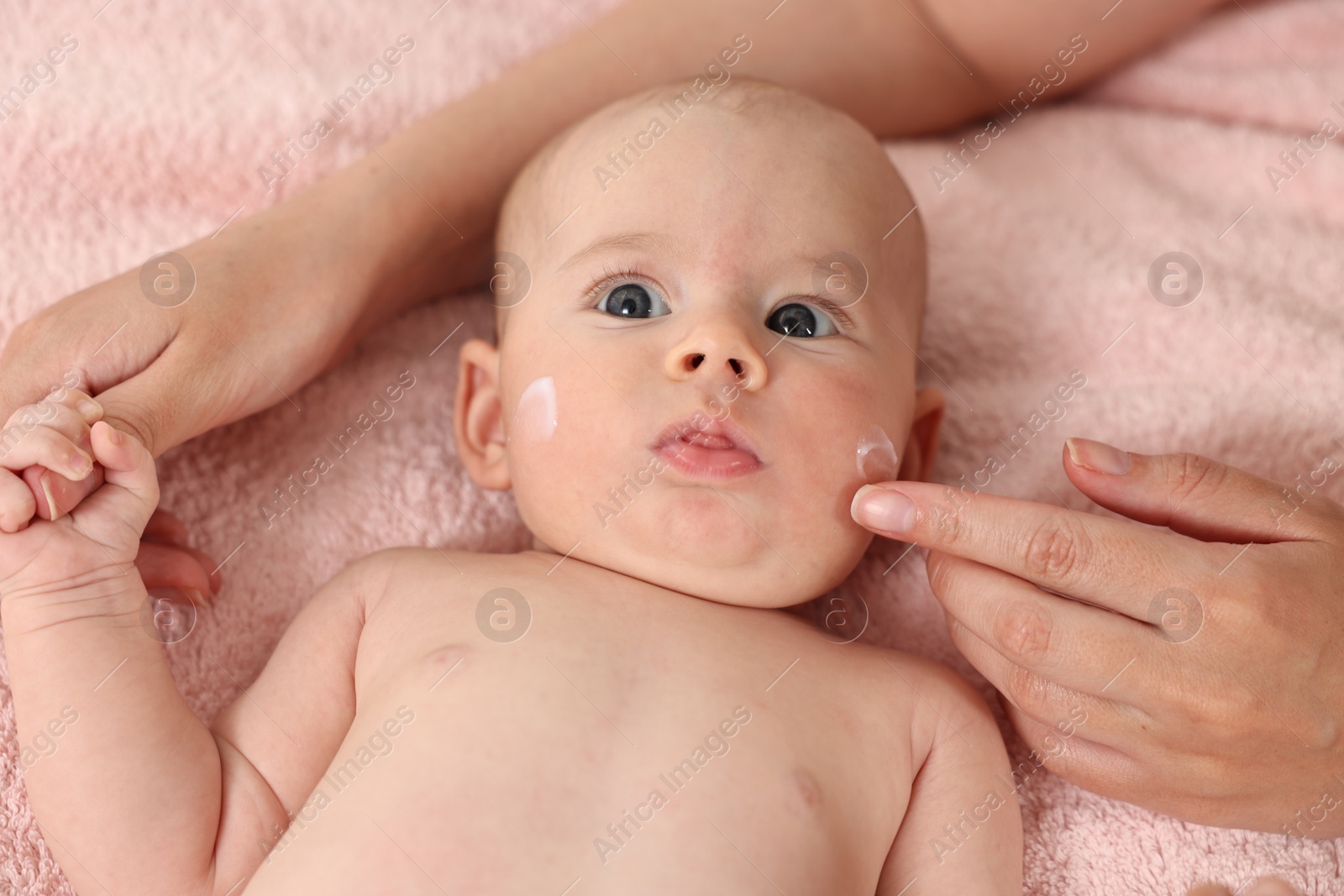 Photo of Woman applying cream onto baby`s face on bed, closeup