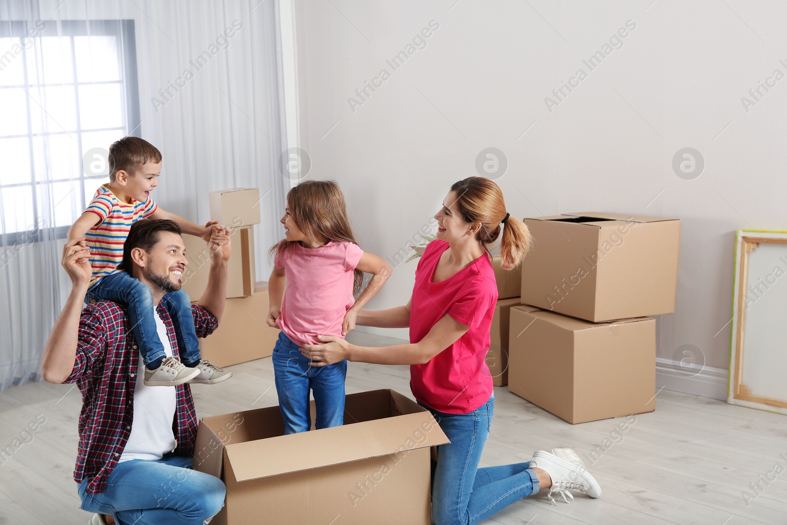 Photo of Happy family playing with cardboard box in their new house. Moving day