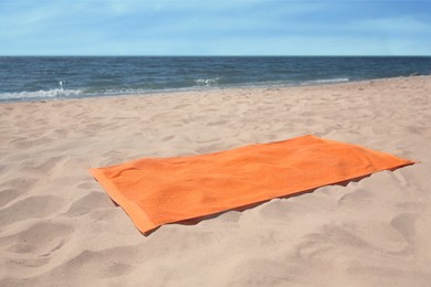 Photo of Soft orange beach towel on sandy seashore