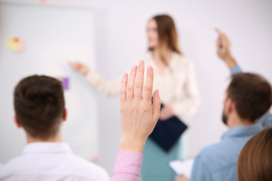 Photo of Woman raising hand to ask question at business training indoors, closeup