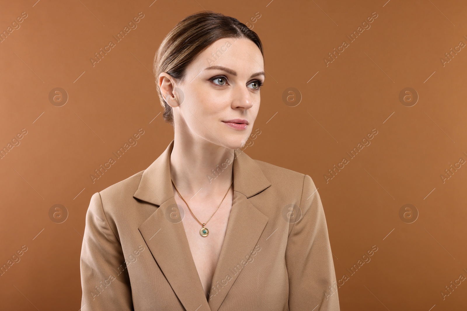 Photo of Beautiful woman with elegant necklace on brown background