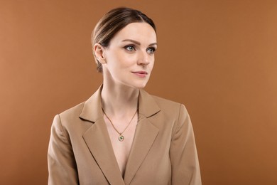 Beautiful woman with elegant necklace on brown background