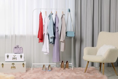 Photo of Clothing rack with stylish women's clothes on hangers in boutique