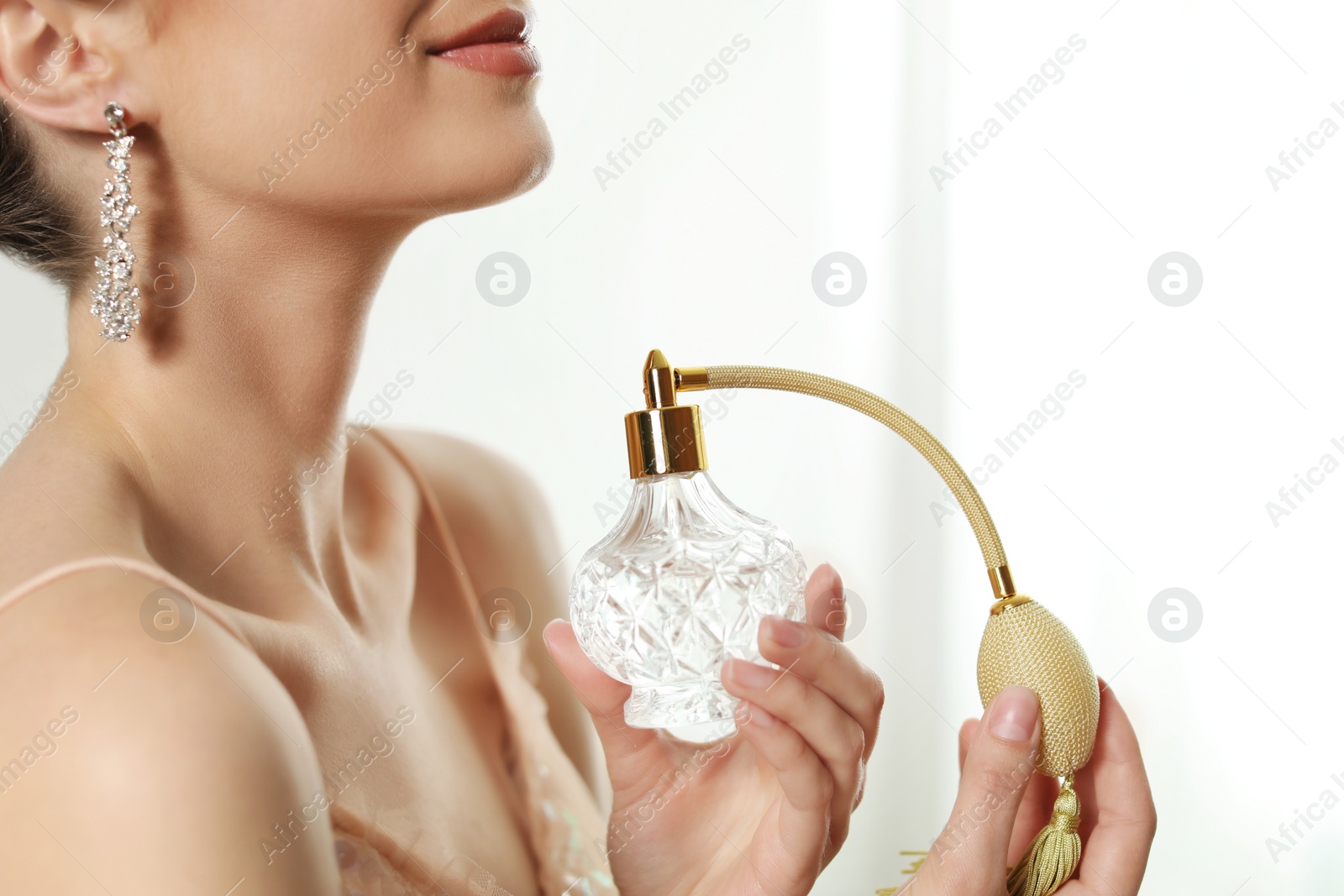 Photo of Young woman applying perfume against blurred background, closeup. Space for text