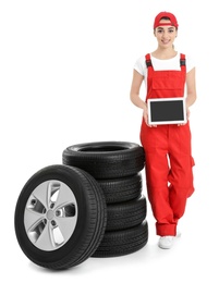 Photo of Female mechanic in uniform with car tires and tablet computer on white background