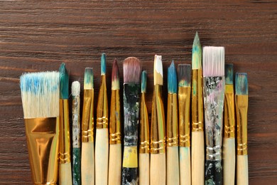 Photo of Many paintbrushes on wooden table, flat lay