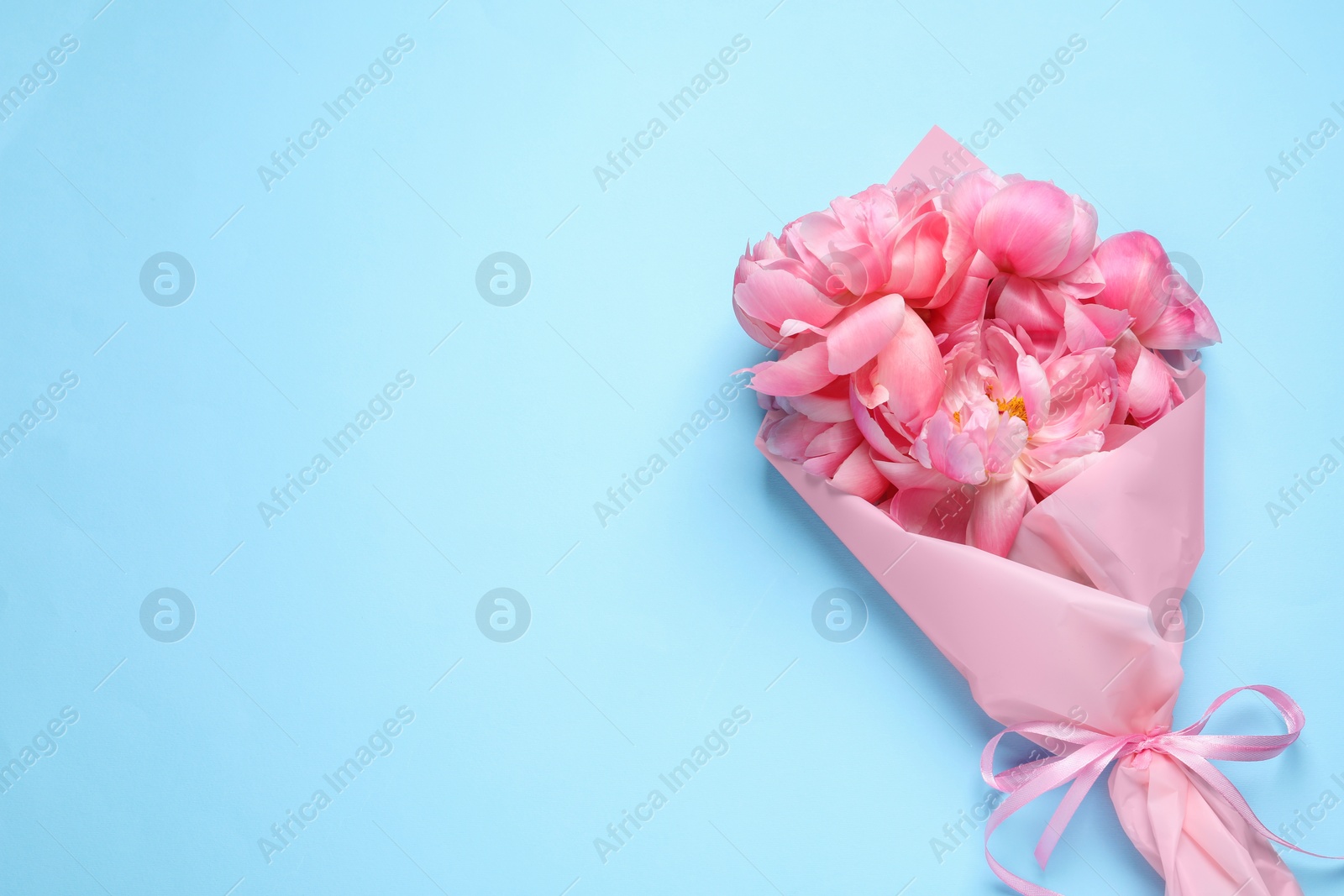 Photo of Beautiful bouquet of pink peonies on light turquoise background, top view. Space for text