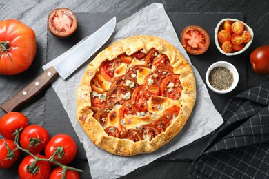 Flat lay composition of tasty galette with tomato and cheese (Caprese galette) on dark textured table