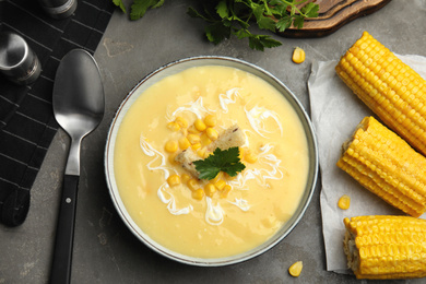 Photo of Delicious corn cream soup served on grey table, flat lay