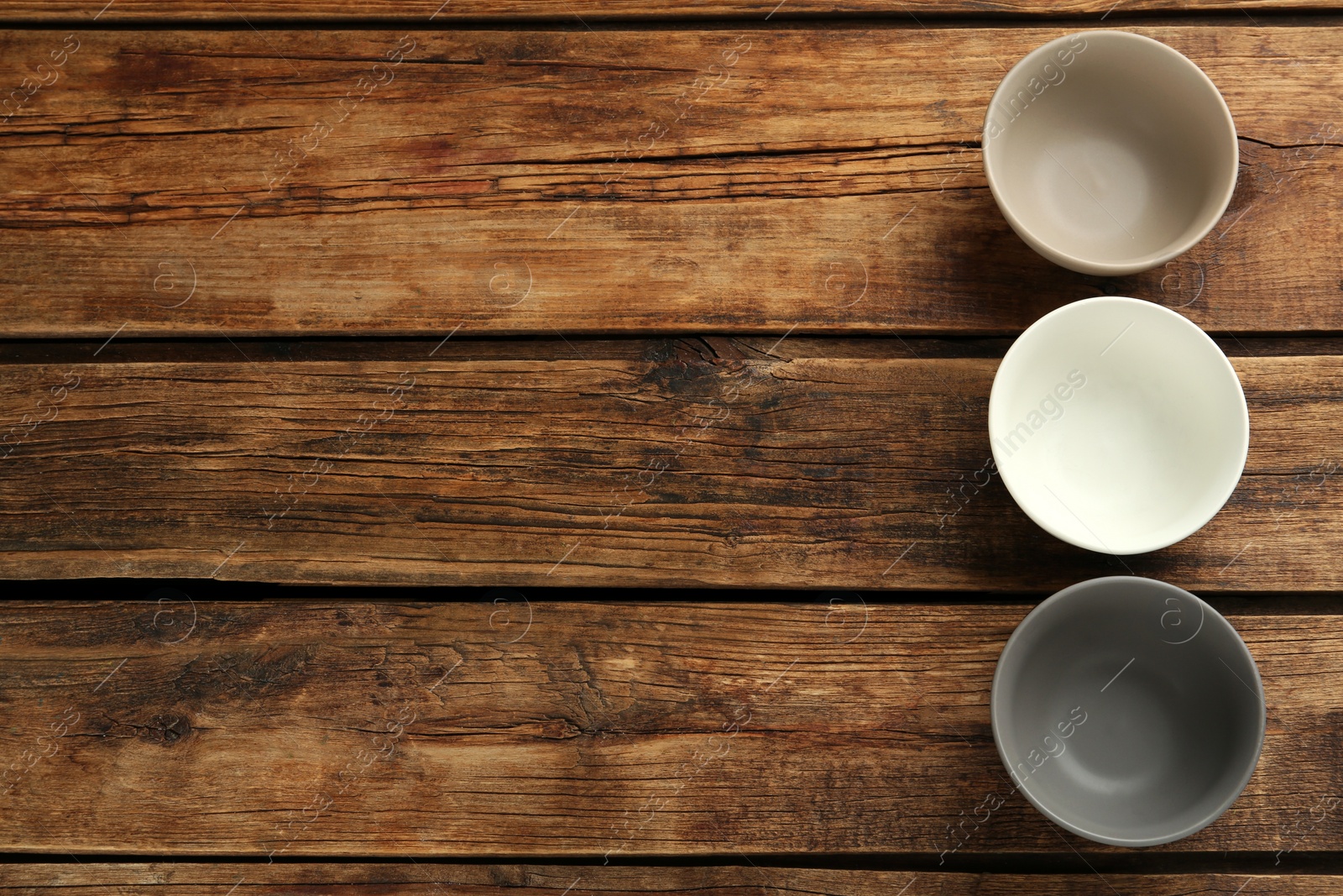 Photo of Stylish empty ceramic bowls on wooden table, flat lay and space for text. Cooking utensils