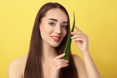 Photo of Young woman with aloe vera leaf on yellow background