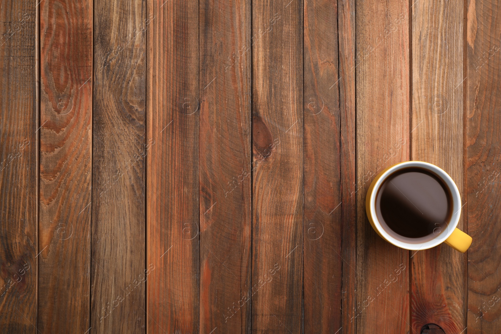 Photo of Ceramic cup with hot aromatic coffee on wooden background, top view