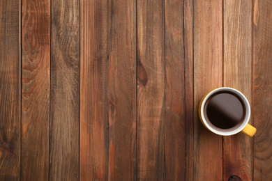 Ceramic cup with hot aromatic coffee on wooden background, top view