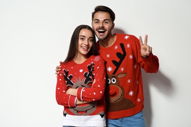 Photo of Young couple in Christmas sweaters on white background
