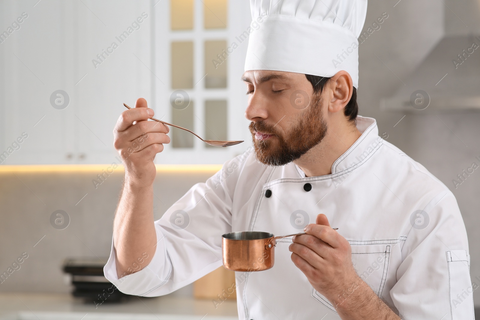 Photo of Professional chef smelling fresh sauce in kitchen