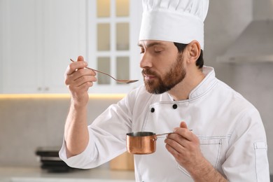 Photo of Professional chef smelling fresh sauce in kitchen