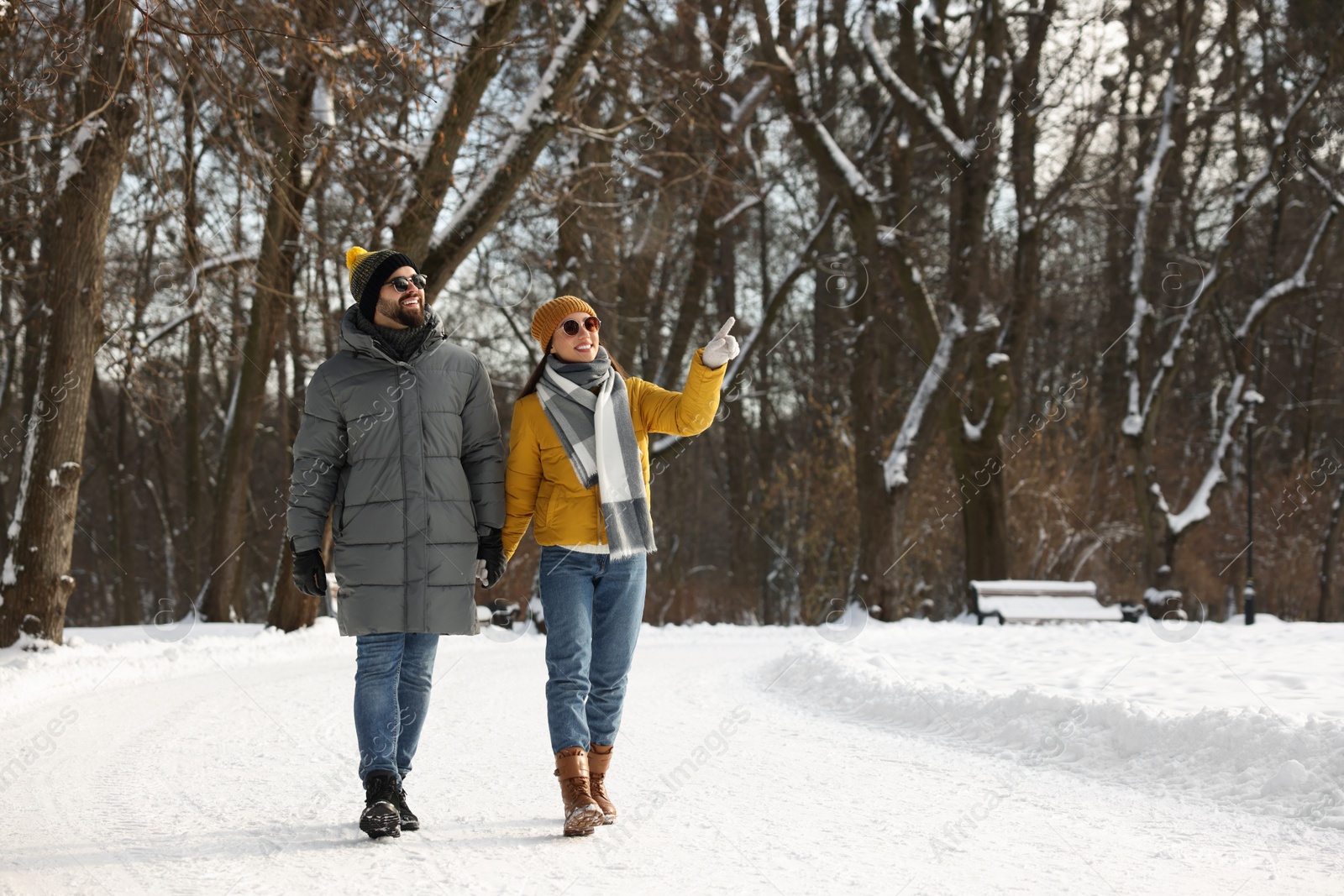 Photo of Beautiful happy couple walking in snowy park on winter day