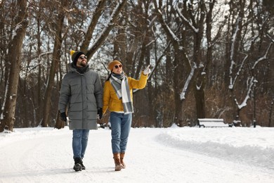 Photo of Beautiful happy couple walking in snowy park on winter day