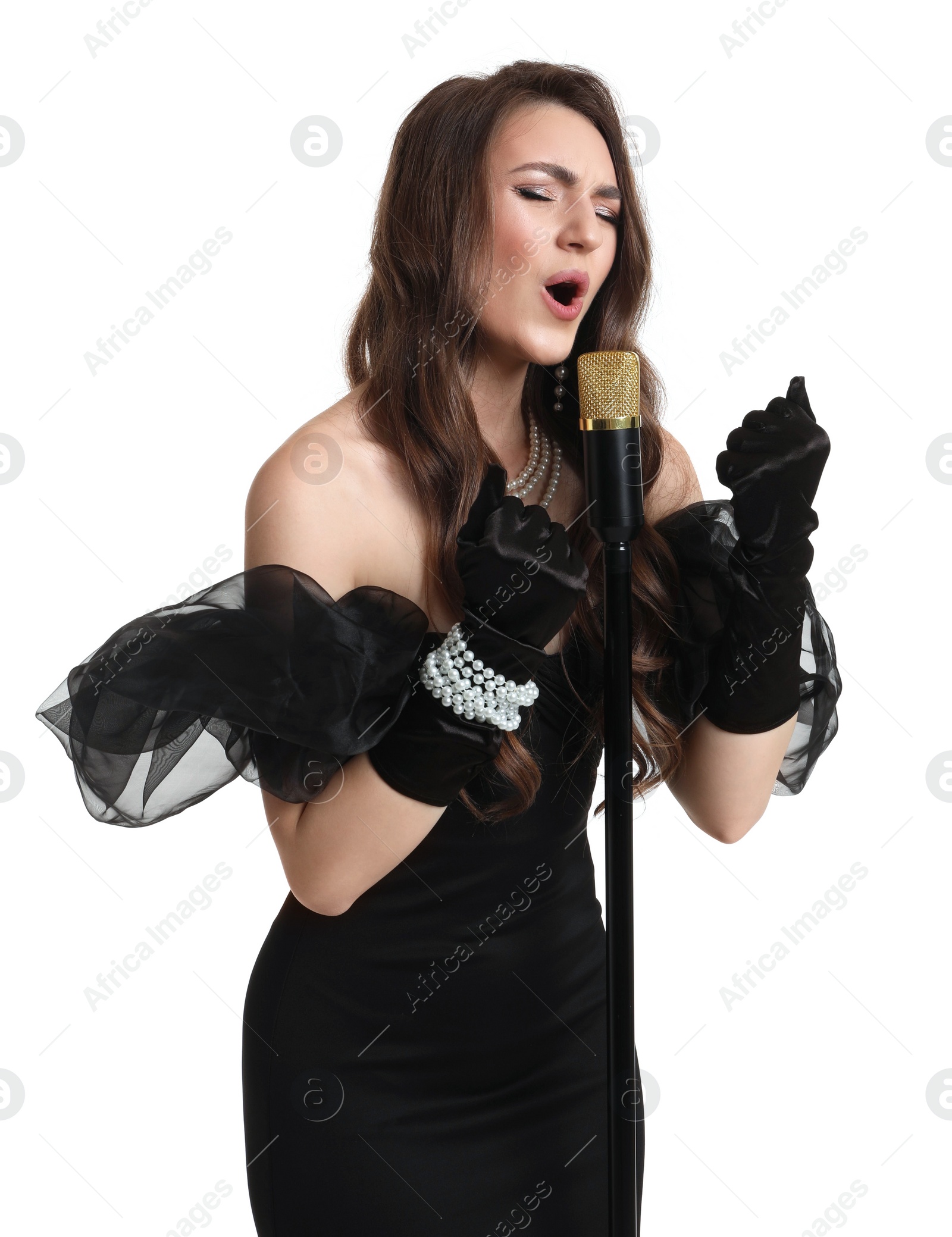 Photo of Beautiful young woman in stylish black dress with microphone singing on white background