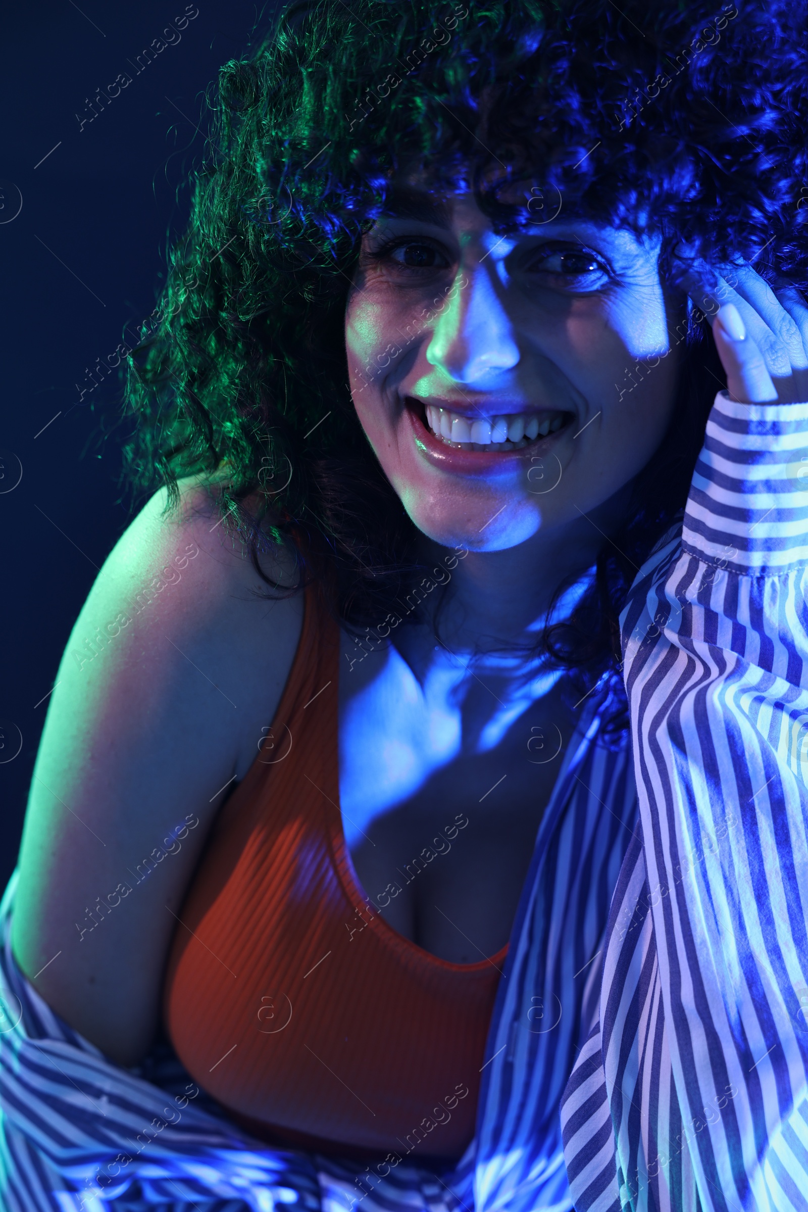 Photo of Beautiful young woman posing on color background in neon lights, closeup