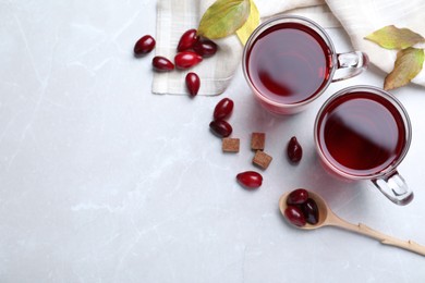 Flat lay composition with fresh dogwood tea and berries on light grey table. Space for text