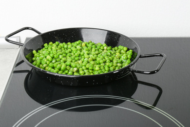 Photo of Cooking frozen sweet peas on induction stove. Vegetable preservation