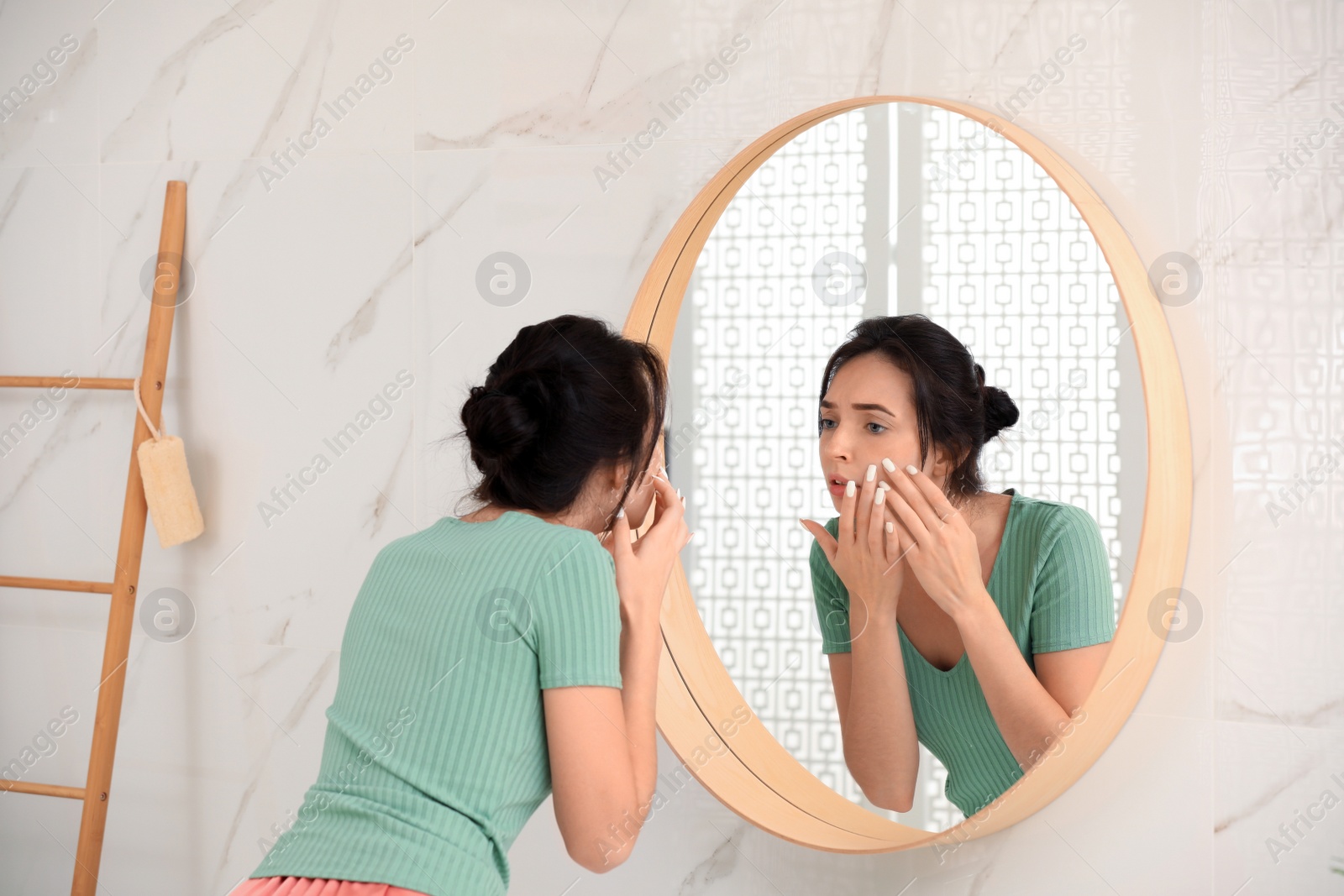 Photo of Beautiful young woman with acne problem near mirror in bathroom