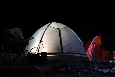Photo of Modern camping tents in wilderness at night