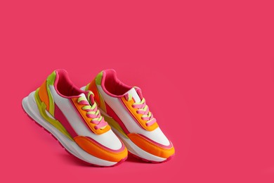 Photo of Pair of stylish colorful sneakers levitating on pink background, space for text