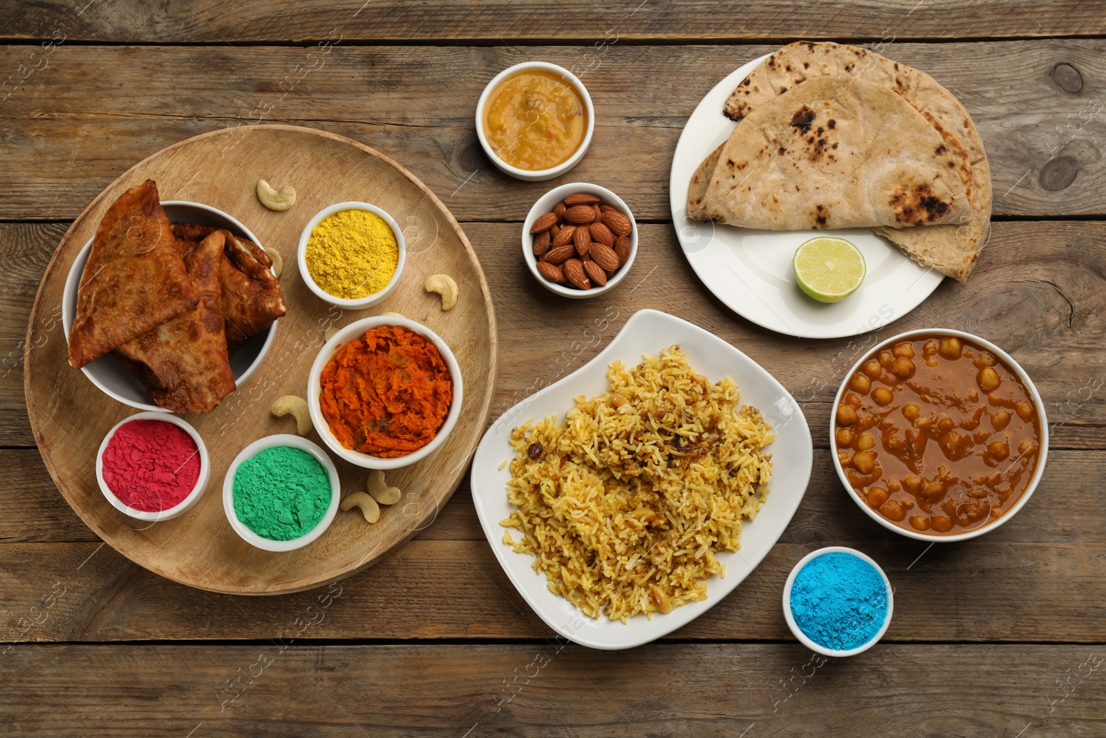 Photo of Traditional Indian food and color powders on wooden table, flat lay. Holi festival celebration