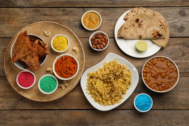 Traditional Indian food and color powders on wooden table, flat lay. Holi festival celebration