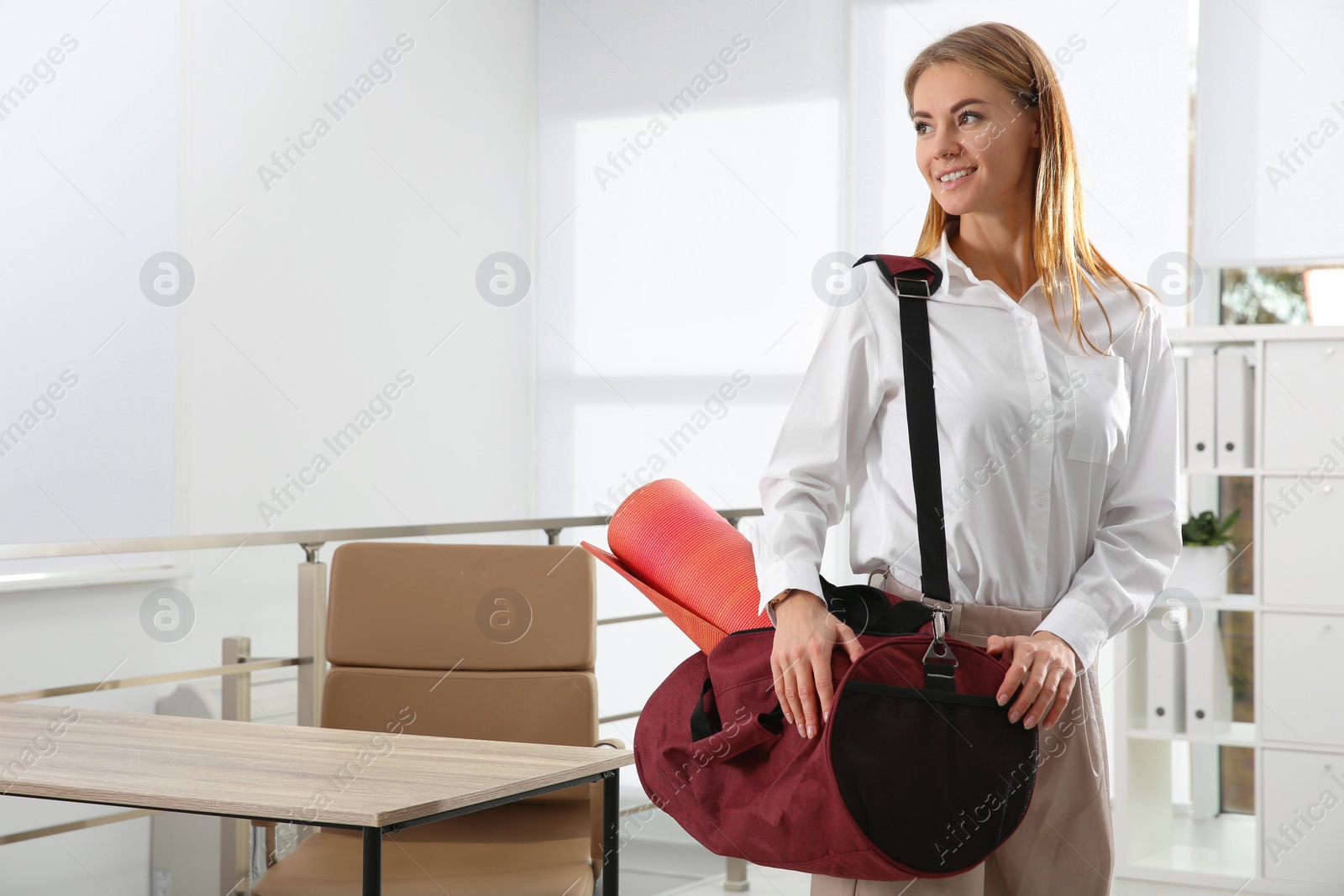 Photo of Beautiful businesswoman with sports bag in office