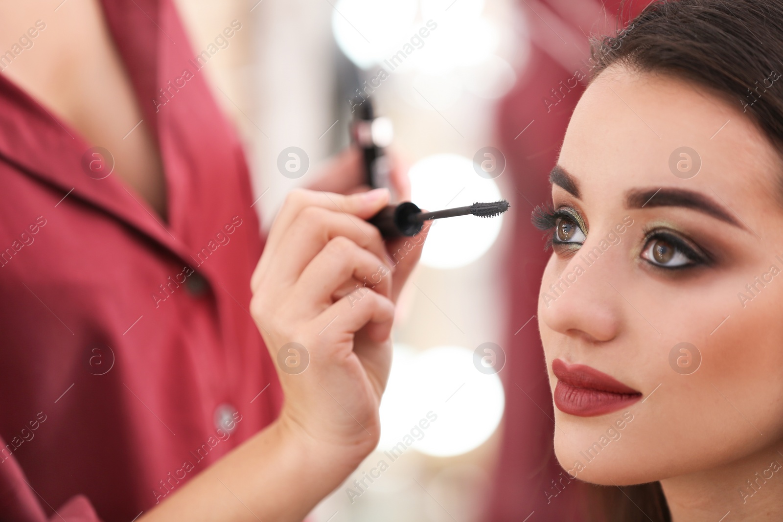 Photo of Professional visage artist applying makeup on woman's face in salon, closeup