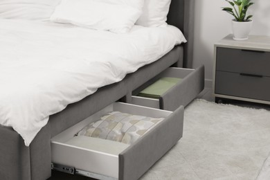 Photo of Storage drawers with bedding under modern bed in room. Space for text