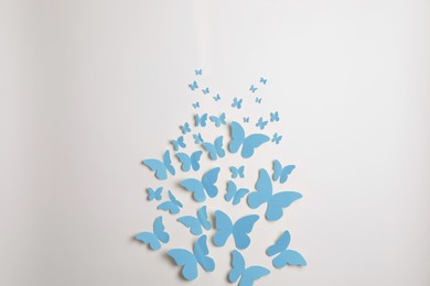 Image of Light blue paper butterflies on white wall