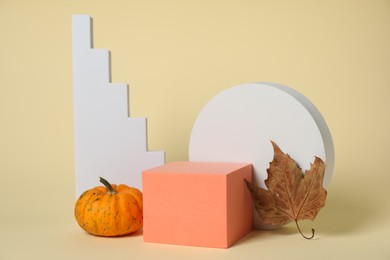 Autumn presentation for product. Geometric figures, pumpkin and dry leaf on beige background