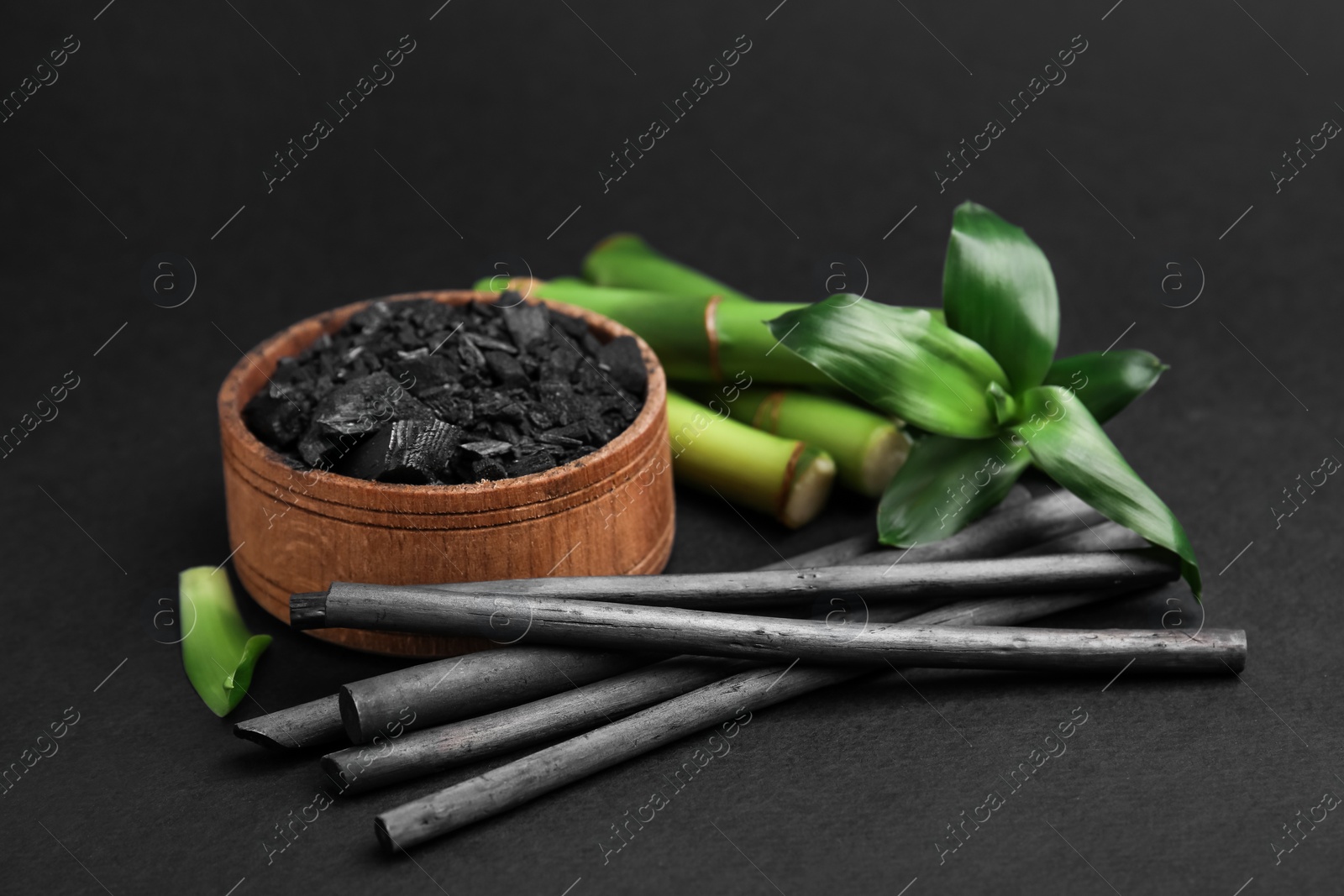 Photo of Fresh bamboo and charcoal on black background