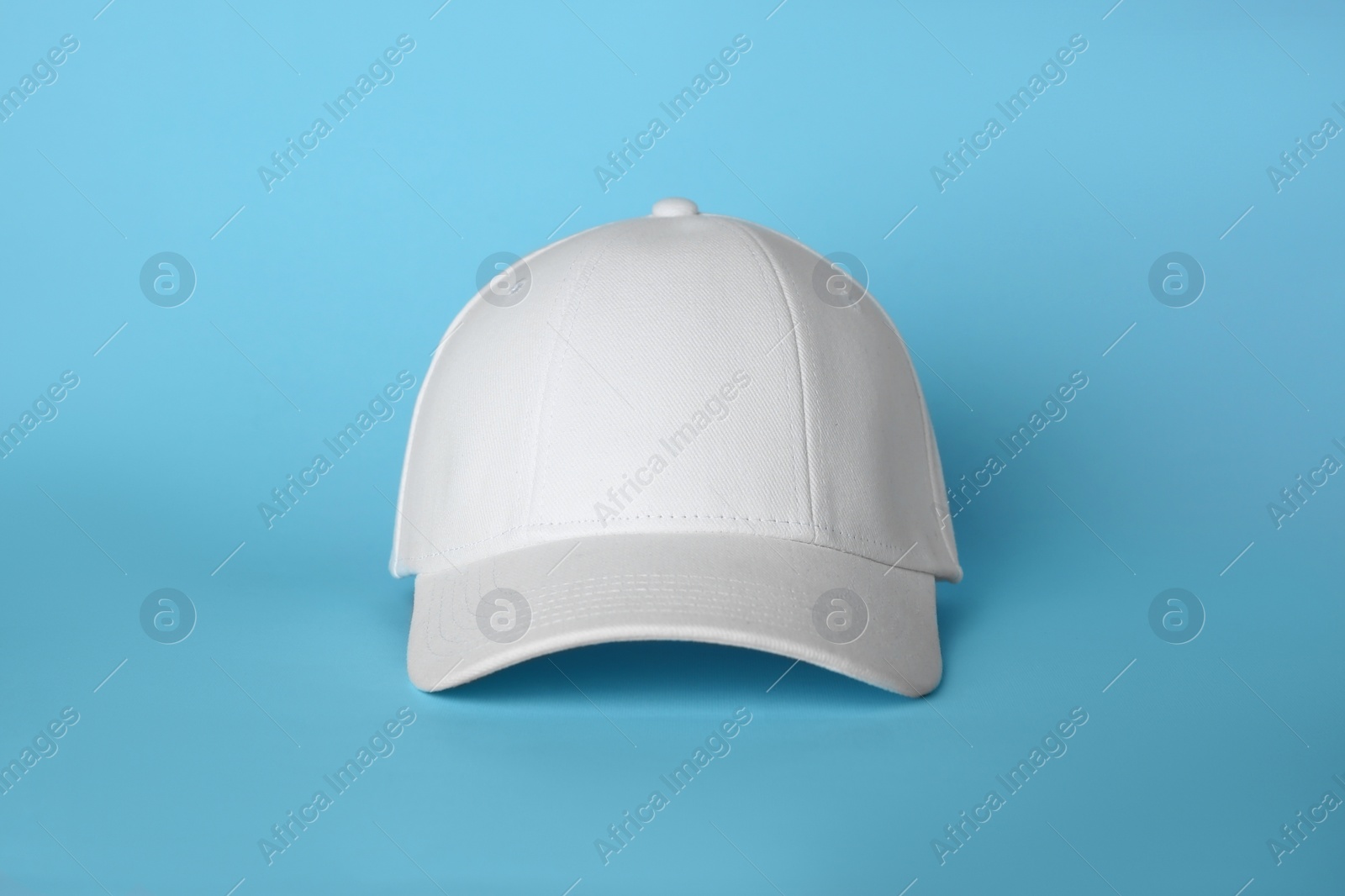 Photo of Stylish white baseball cap on light blue background