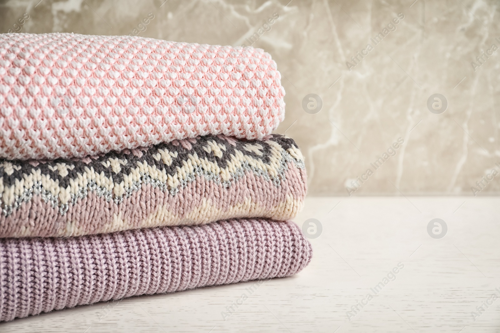 Photo of Stack of warm knitted clothes on table