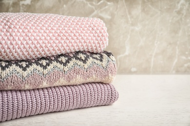 Photo of Stack of warm knitted clothes on table