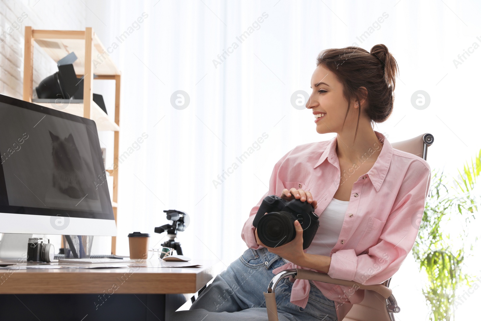 Photo of Professional photographer with camera working at table in office