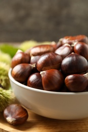 Photo of Fresh sweet edible chestnuts in bowl, closeup
