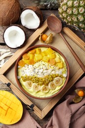 Tasty smoothie bowl with fresh fruits served on wooden table, flat lay