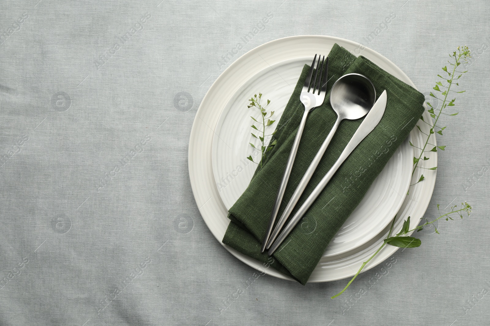 Photo of Stylish setting with cutlery, leaves and plates on grey table, top view. Space for text